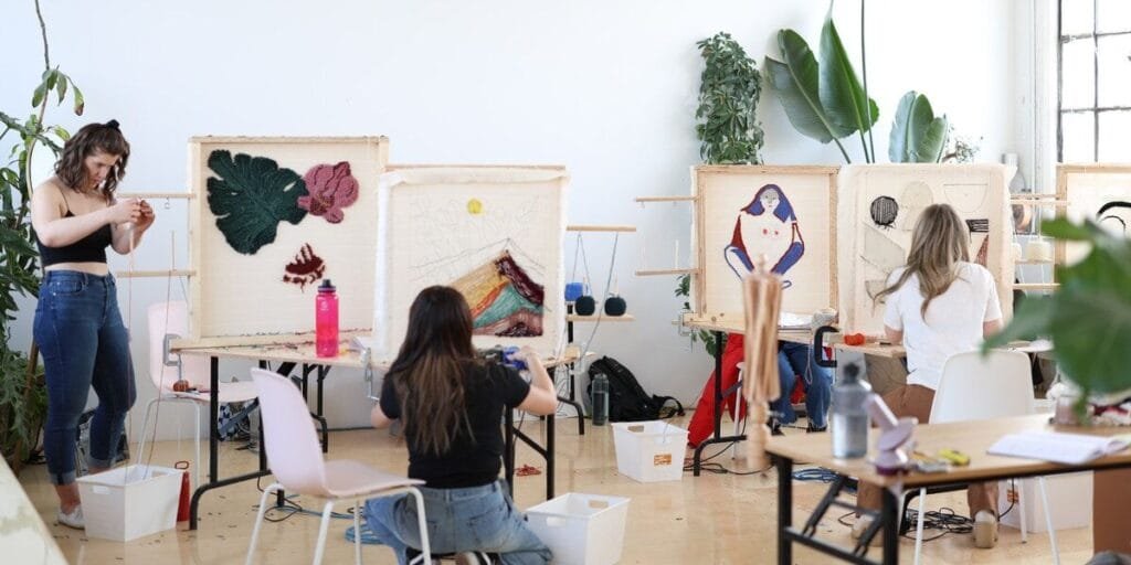 a woman sitting in a chair in front of several art pieces